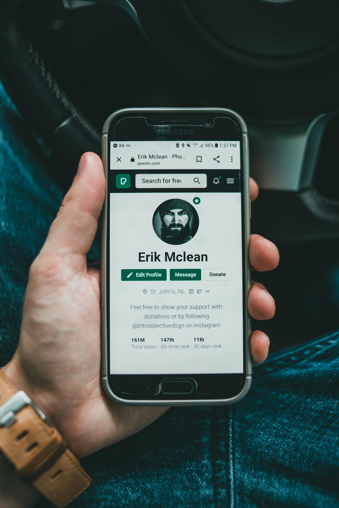 A smartphone displaying a user's social media profile in a person's hand.